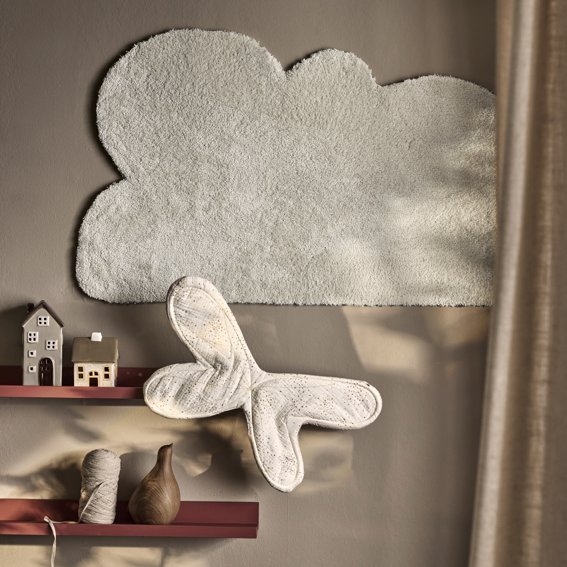 en måttbeställd matta formad som ett moln hänger på en grå vägg