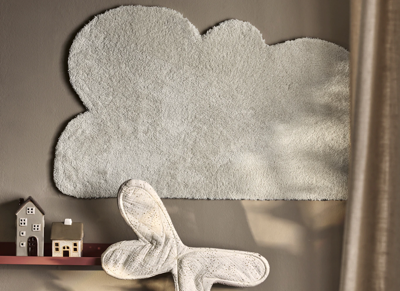 en måttbeställd matta formad som ett moln hänger på en grå vägg