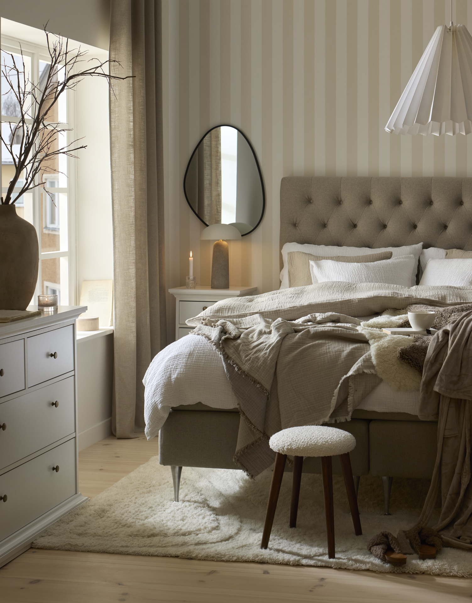 en grå kontinentalsäng står i ett ljust sovrum  