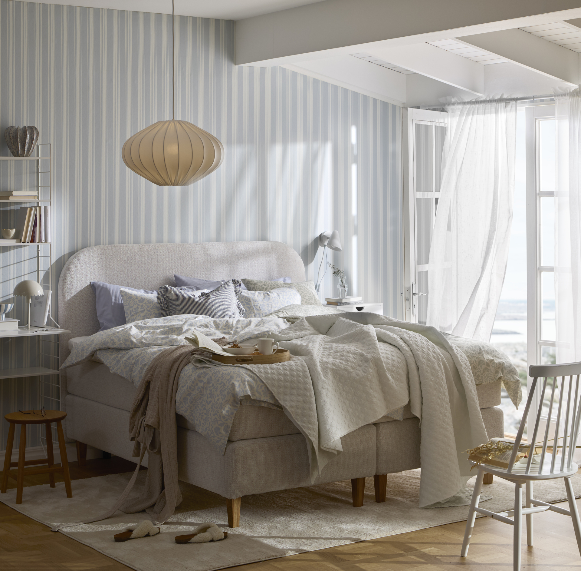 Ett ljust sovrum med en kontinentalsäng som står på en beige matta.