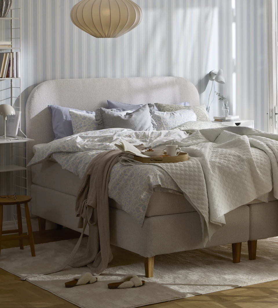 Ett ljust sovrum med en kontinentalsäng som står på en beige matta.