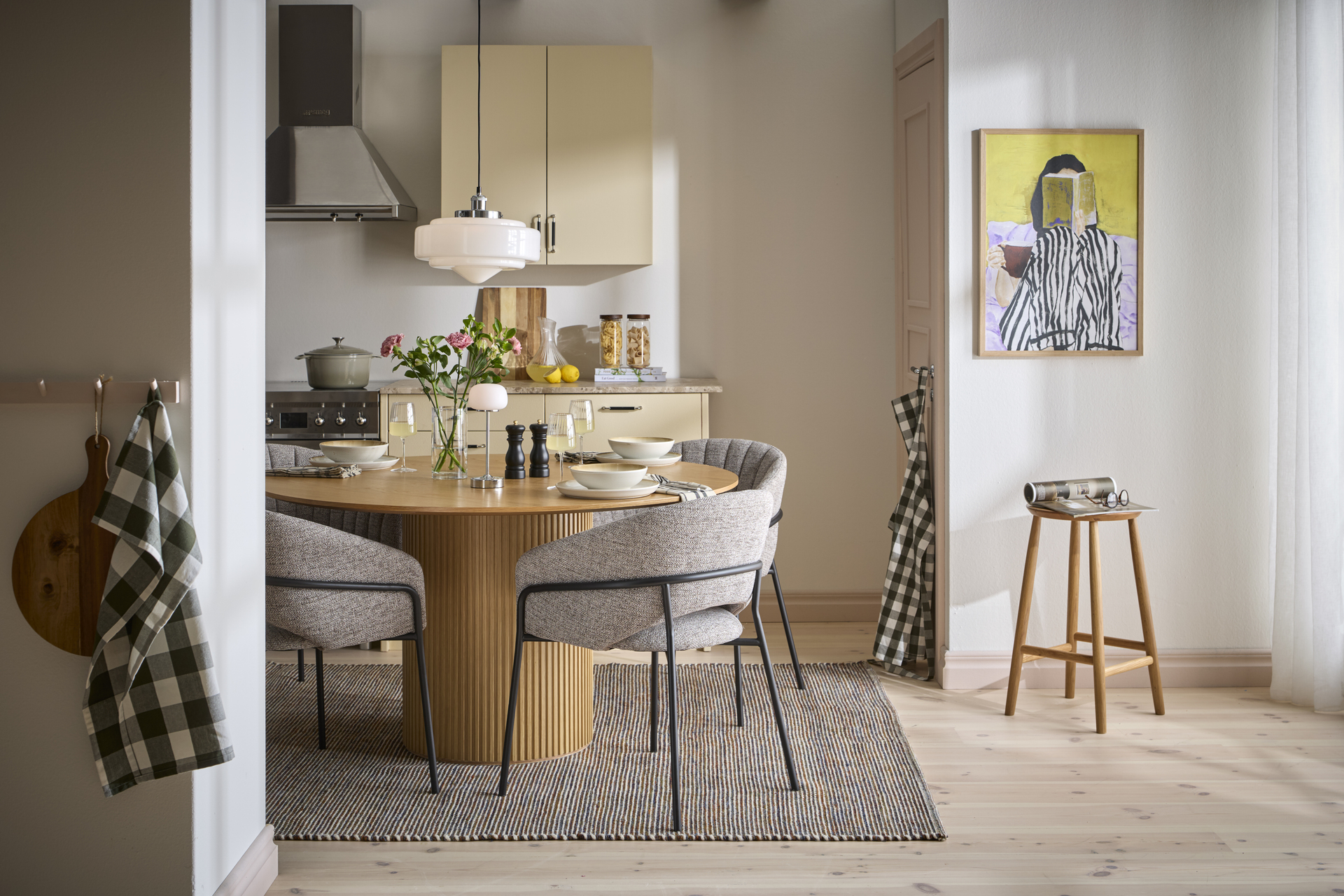 ett runt matbord med fyra grå stolar står på en brun matta i ett gult kök