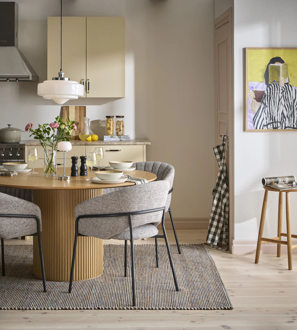 ett runt matbord med fyra grå stolar står på en brun matta i ett gult kök