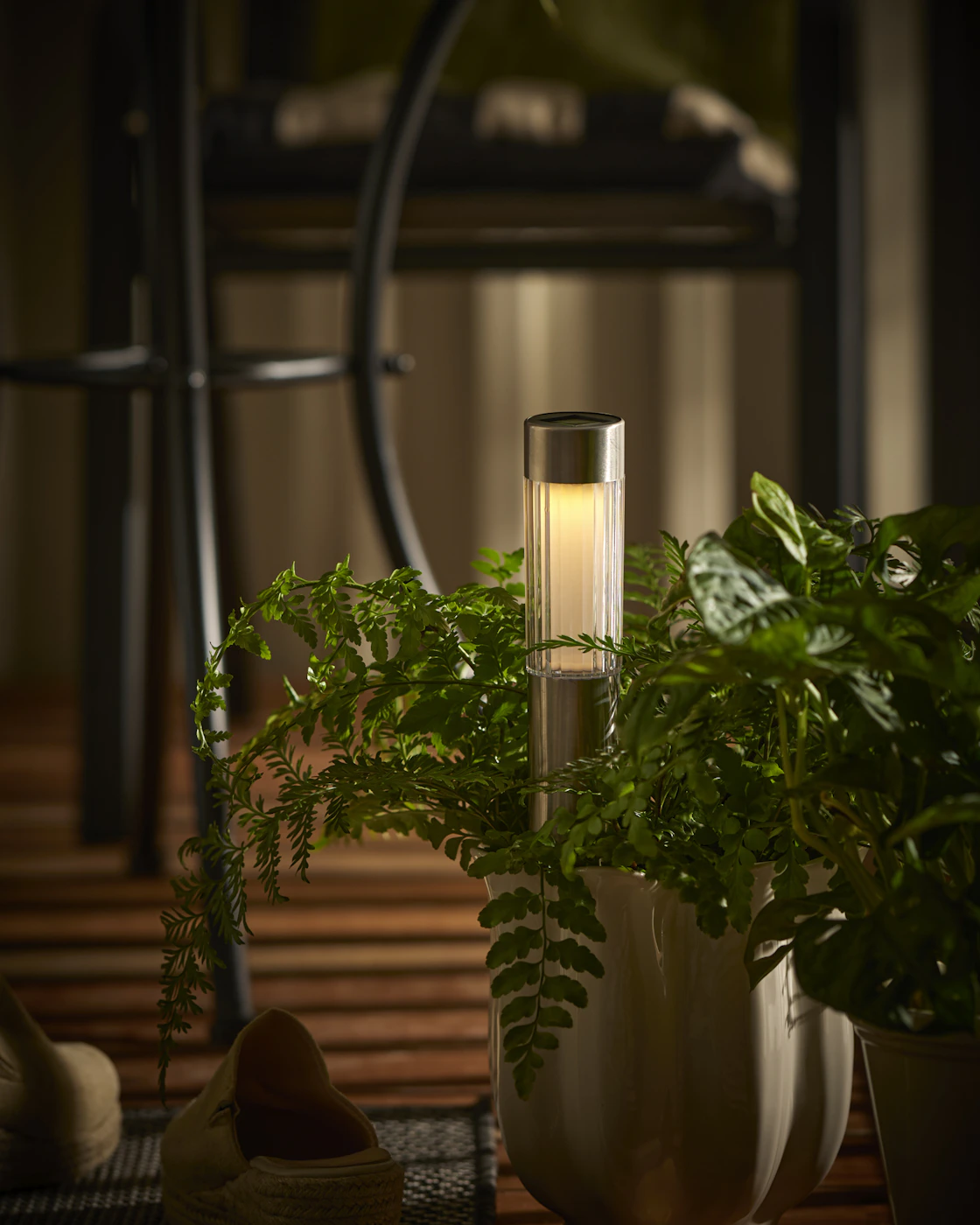 En kromad solcellslampa är nedstucken i en kruka.