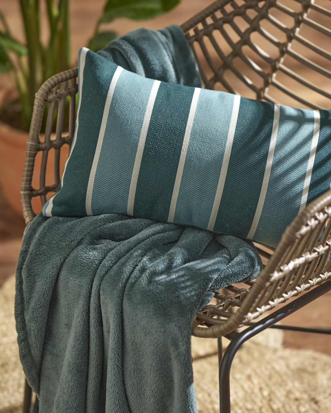 En vattenavvisande utekudde i blårandigt mönster ligger i en utestol.