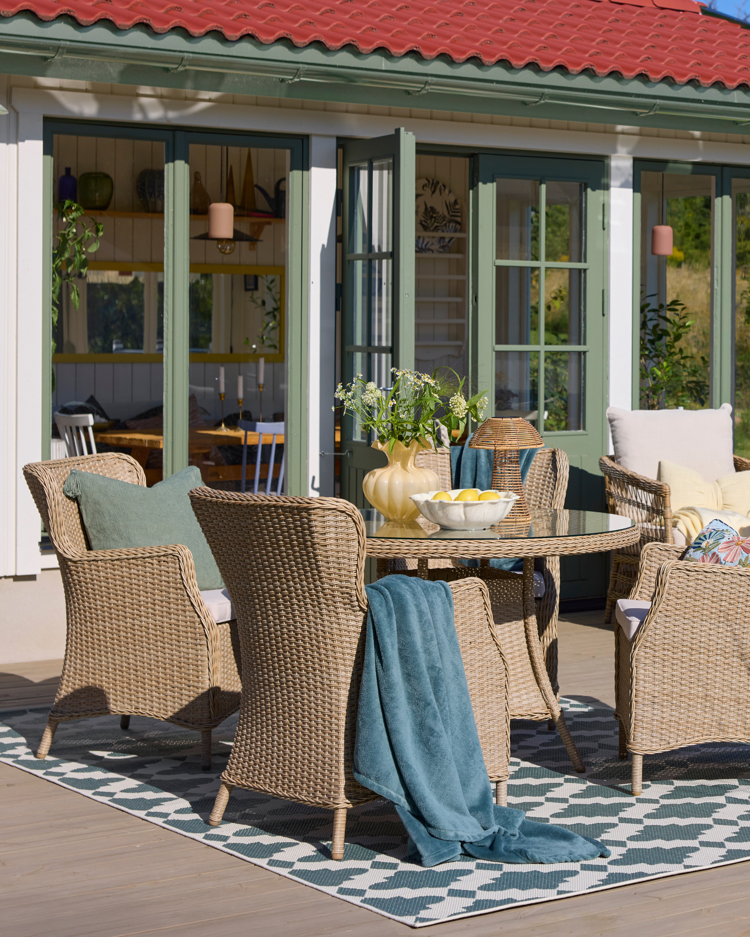 En utegrupp med ett runt bord och fyra fåtöljer i konstrotting.