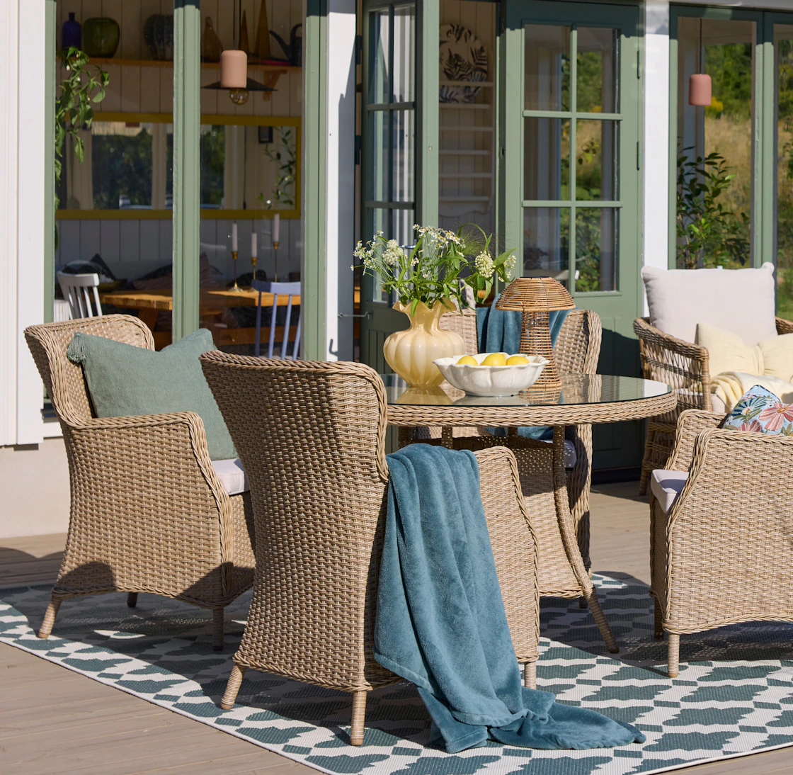 En utegrupp med ett runt bord och fyra fåtöljer i konstrotting.