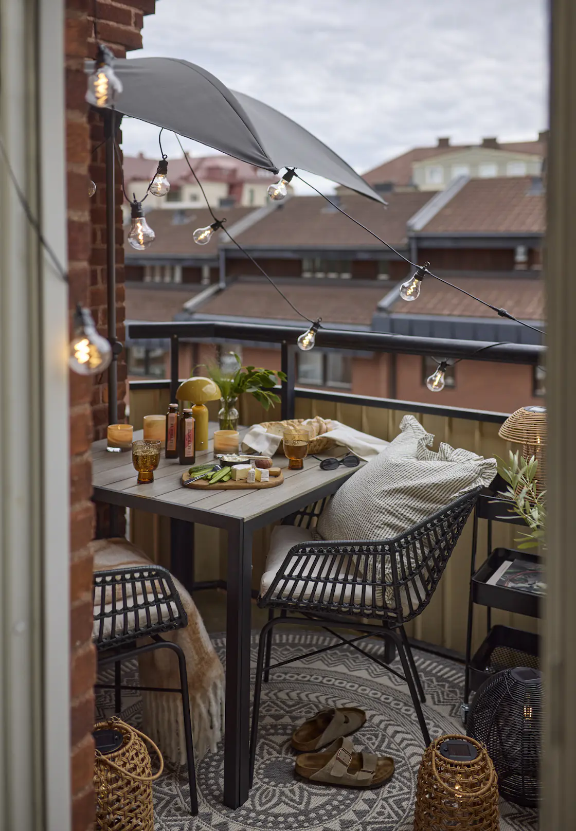 Två svarta utekarmstolar av konstrotting och matchande bord står på en balkong.