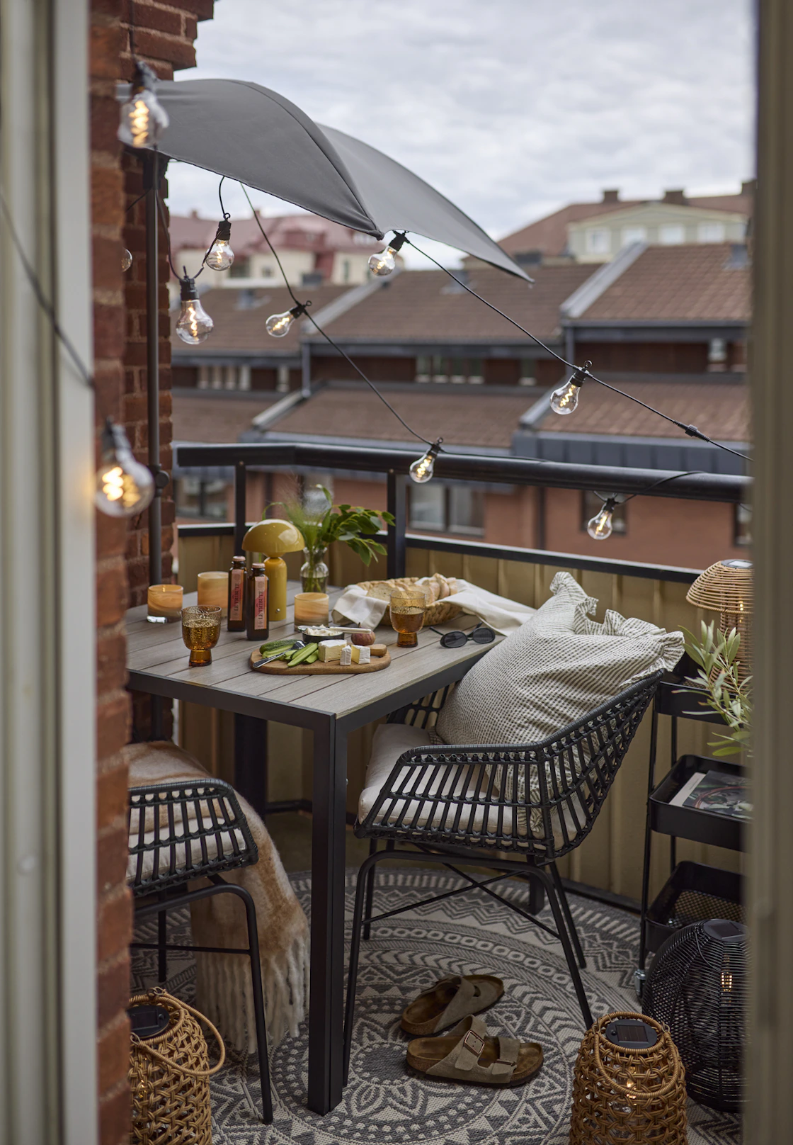Två svarta utekarmstolar av konstrotting och matchande bord står på en balkong.