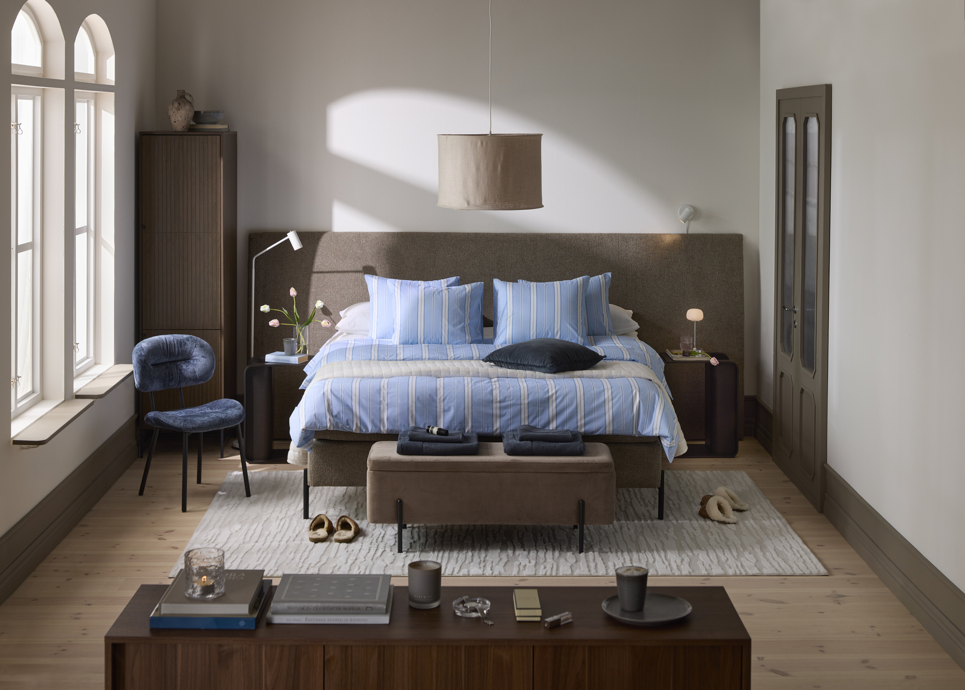 en kontinentalsäng med en bred sänggavel står i ett sovrum med mycket mörka detaljer. 