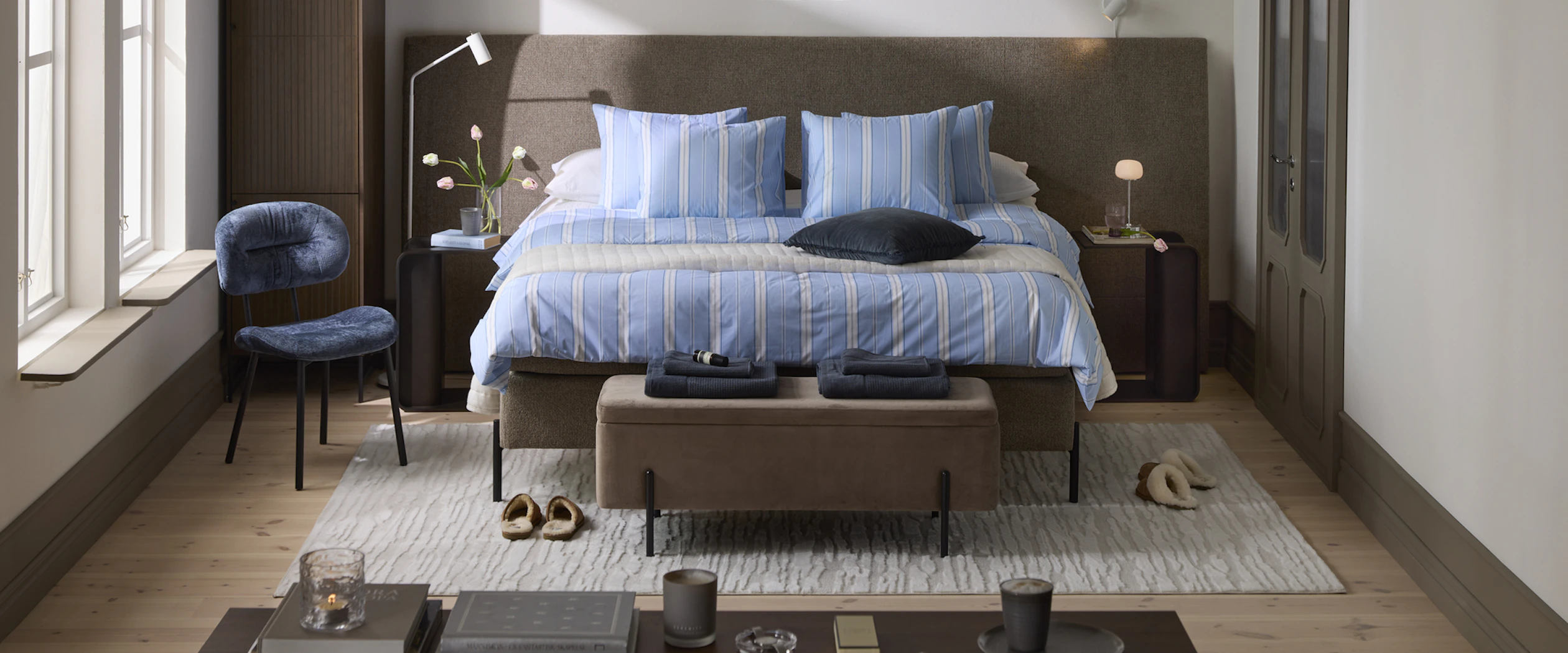 en kontinentalsäng med en bred sänggavel står i ett sovrum med mycket mörka detaljer.