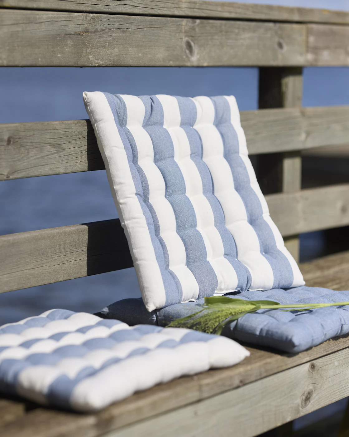 Två dynor med blåvita ränder på en brygga.