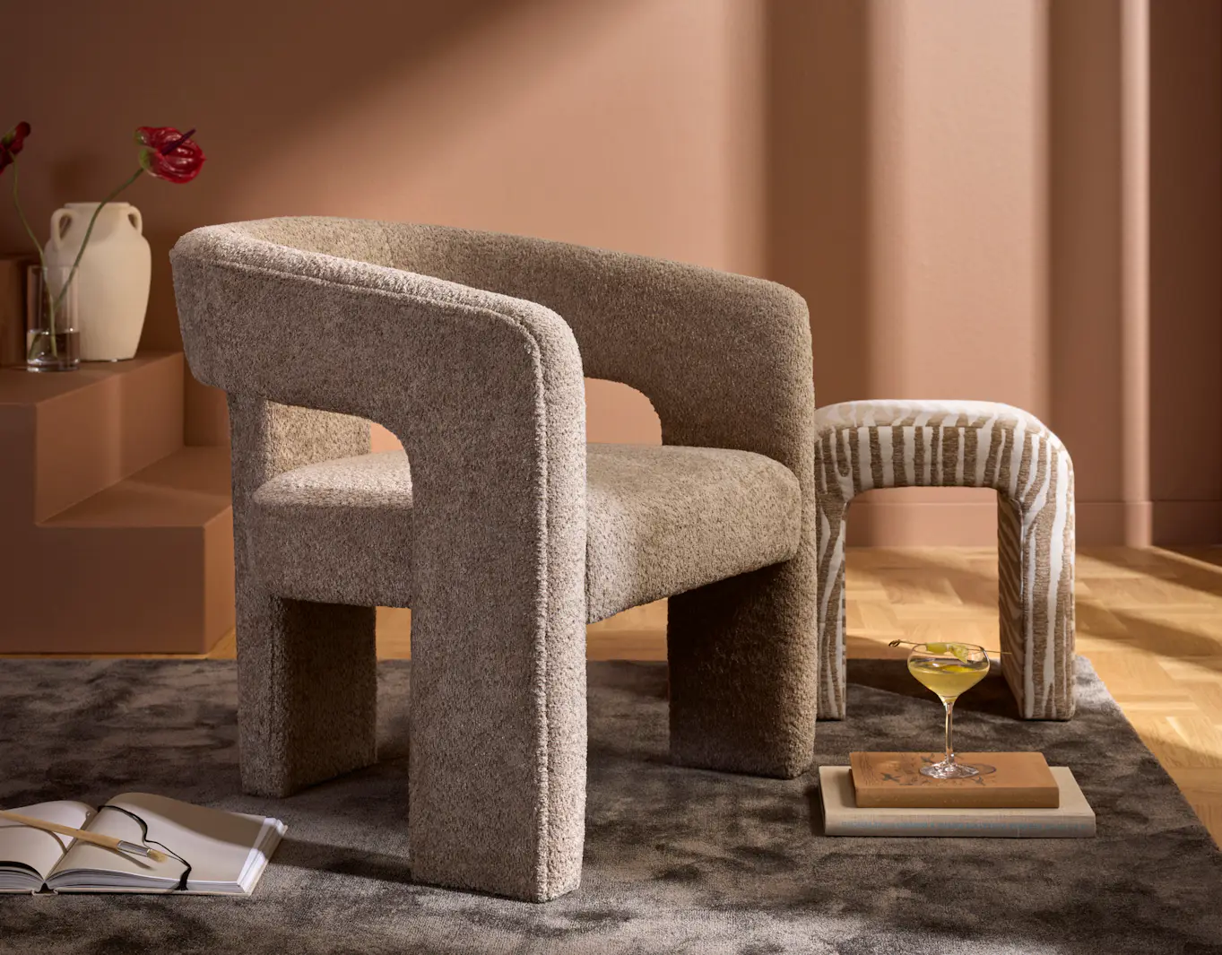 I ett terracottarött rum står en beige fåtölj i modern design