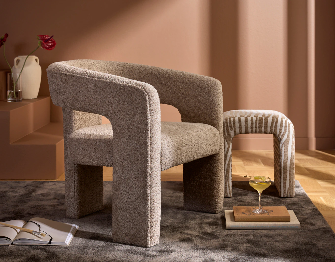 I ett terracottarött rum står en beige fåtölj i modern design