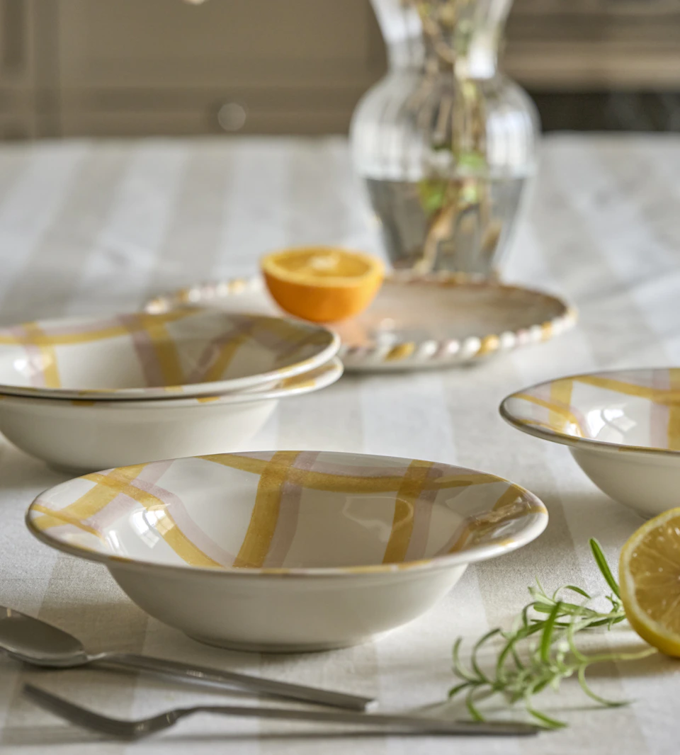 gulmönstrat porslin i olika former står på en randig duk