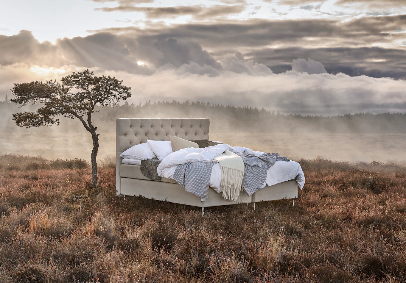 en kontinentalsäng står bäddad med sängkläder i olika ljusa toner på en äng