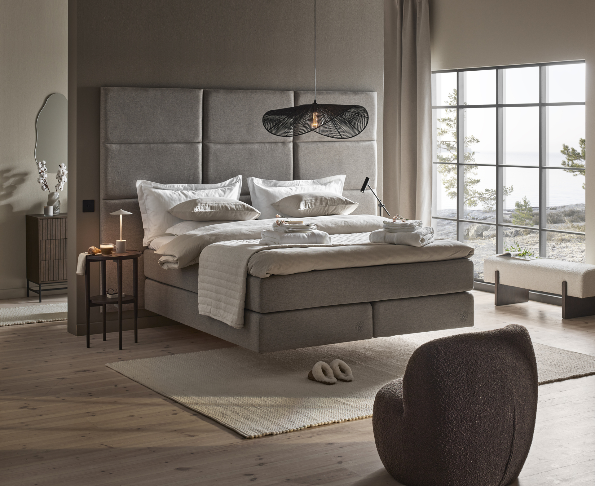 en grå kontinentalsäng med hög sänggavel står i ett sovrum 