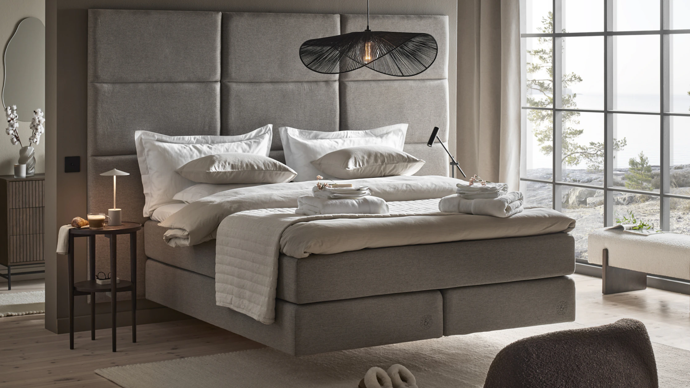 en grå kontinentalsäng med hög sänggavel står i ett sovrum