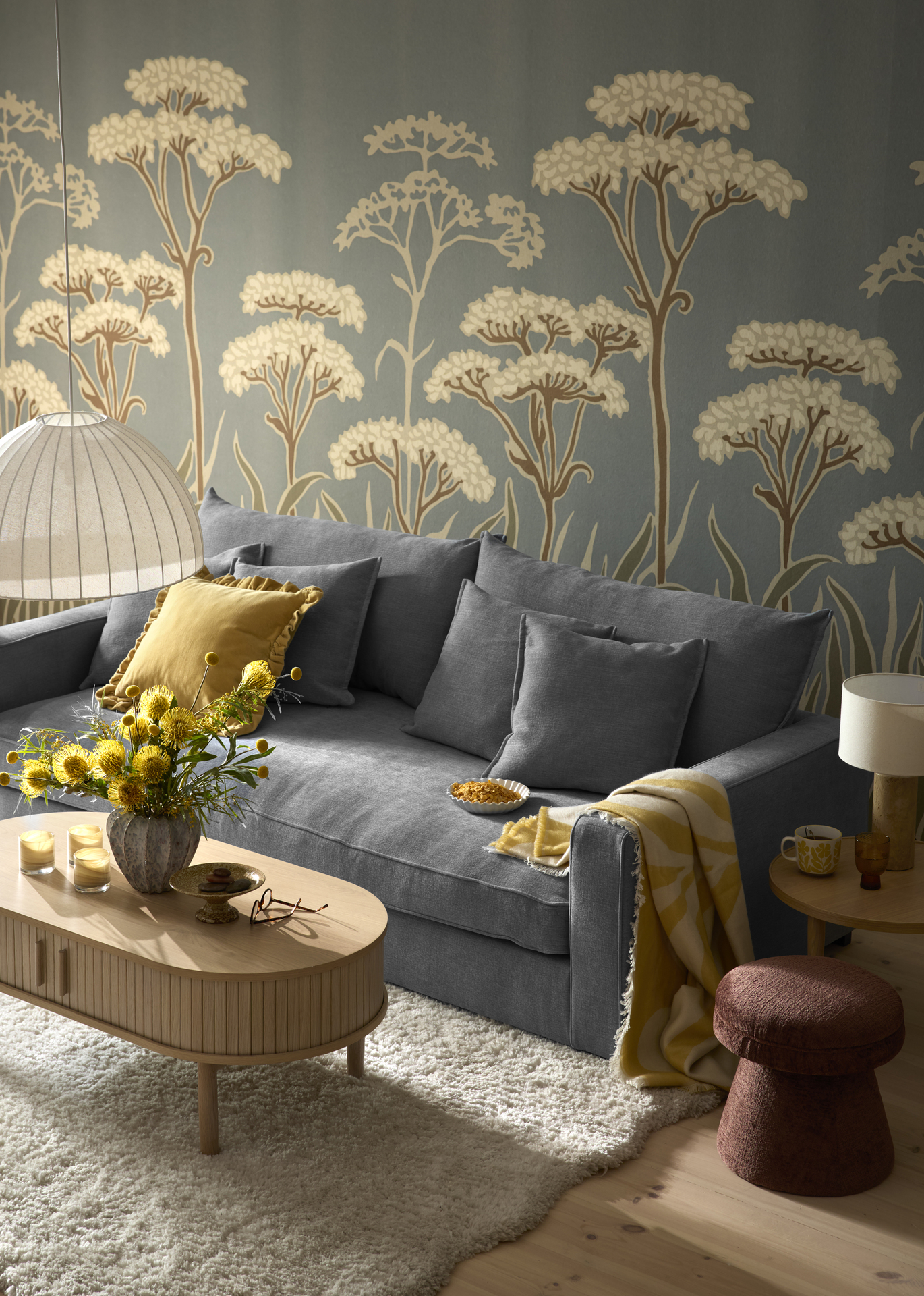 Framför en blå soffa står ett soffbord i vitbetsat trä