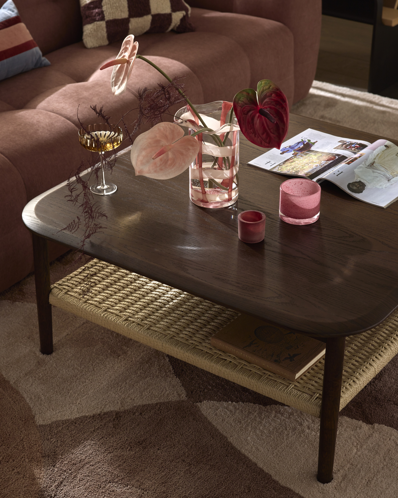 En närbild på ett kvadratiskt soffbord i mörkt trä med en flätad hylla under