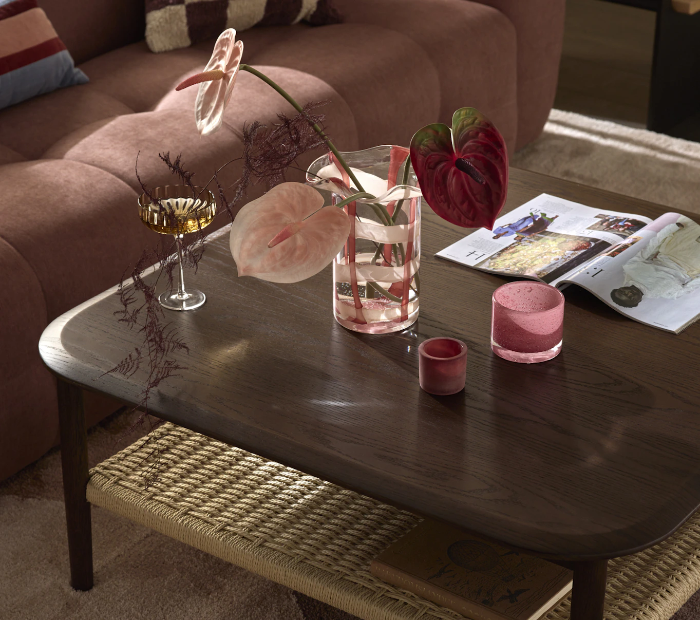 En närbild på ett kvadratiskt soffbord i mörkt trä med en flätad hylla under