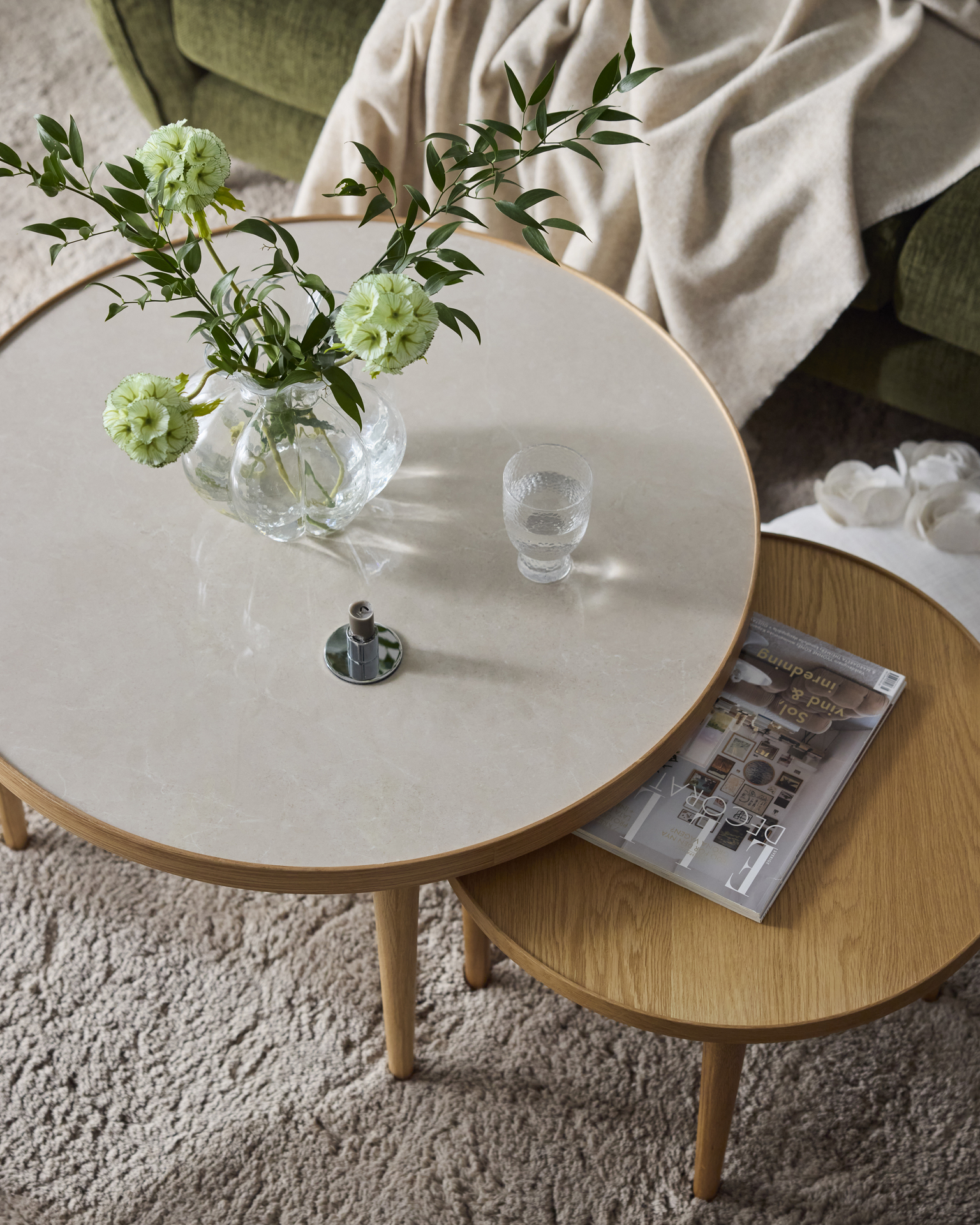 Två runda satsbord står på en ljus ryamatta, en i skiva i stenimitation och en med en skiva i ljust trä