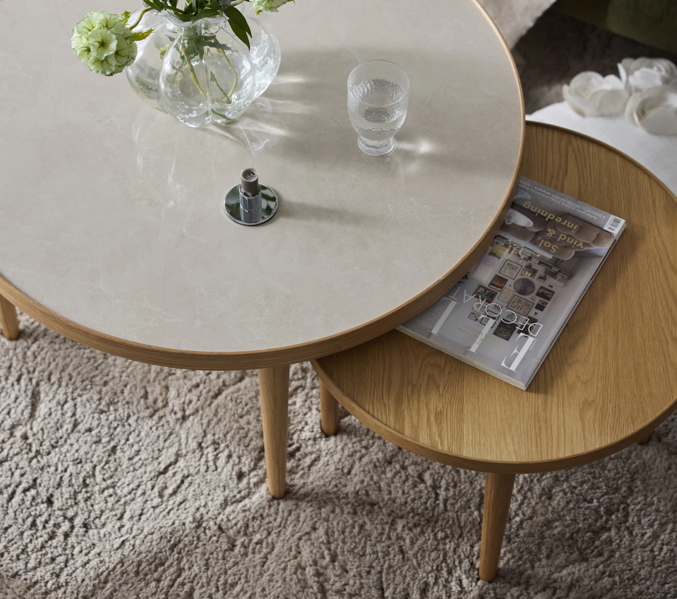 Två runda satsbord står på en ljus ryamatta, en i skiva i stenimitation och en med en skiva i ljust trä