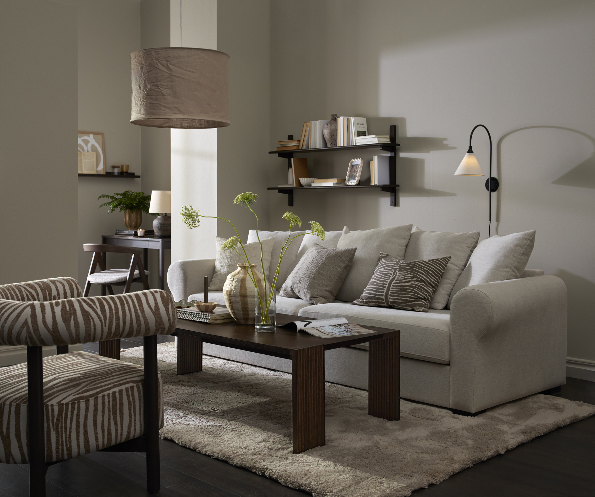 Framför en vit soffa står ett rektangulärt soffbord i mörkt trä med ribbade ben