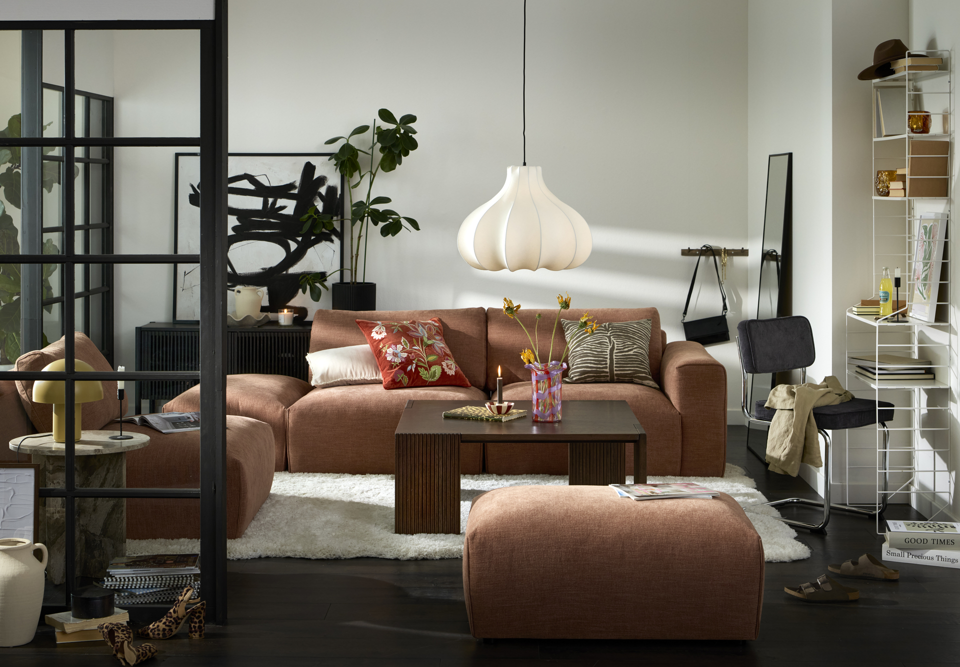 Framför en rostfärgad modulsoffa står ett kvadratiskt soffbord i mörkt trä med ribbade ben