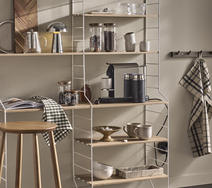 På en stor vägghylla står en kaffemaskin, muggar och andra köksatteraljer