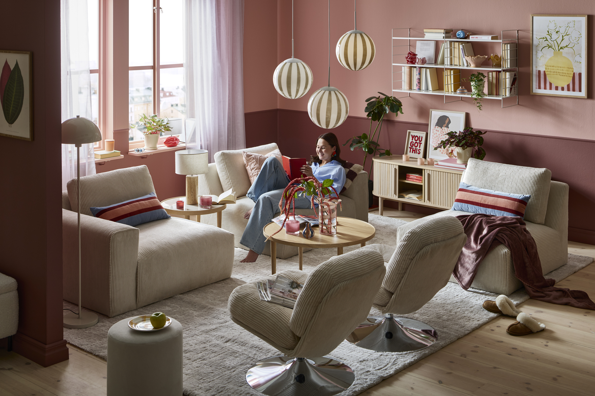 Ung kvinna halvligger i trendig soffa och läser i en bok i färggrannt vardagsrum av modern stil. 