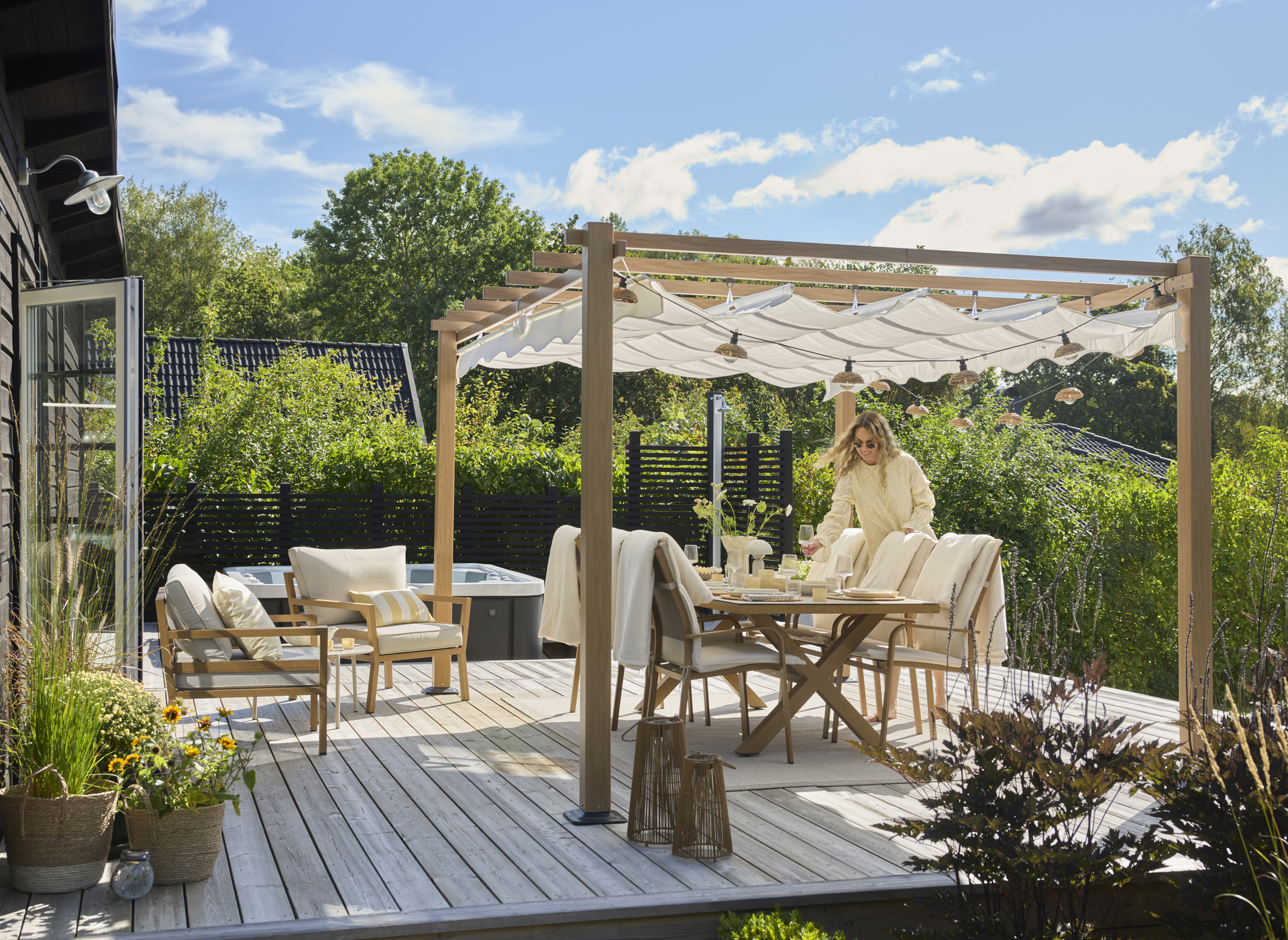 Uteplats med utematgrup under en stor pergola en solig sommardag i en modern villaträdgård. 