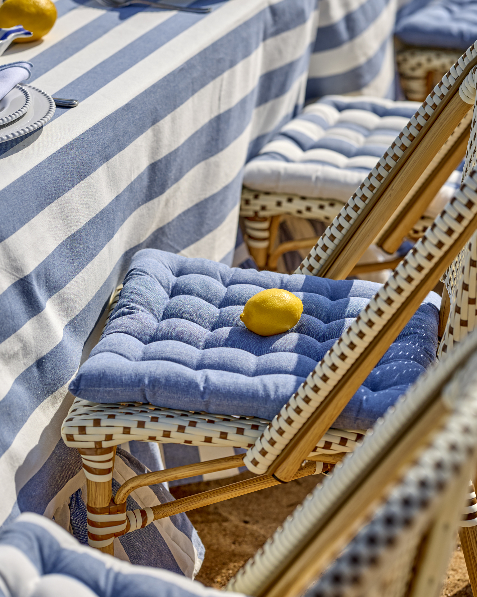 På en stol på stranden ligger en blå sittdyna samt en citron.