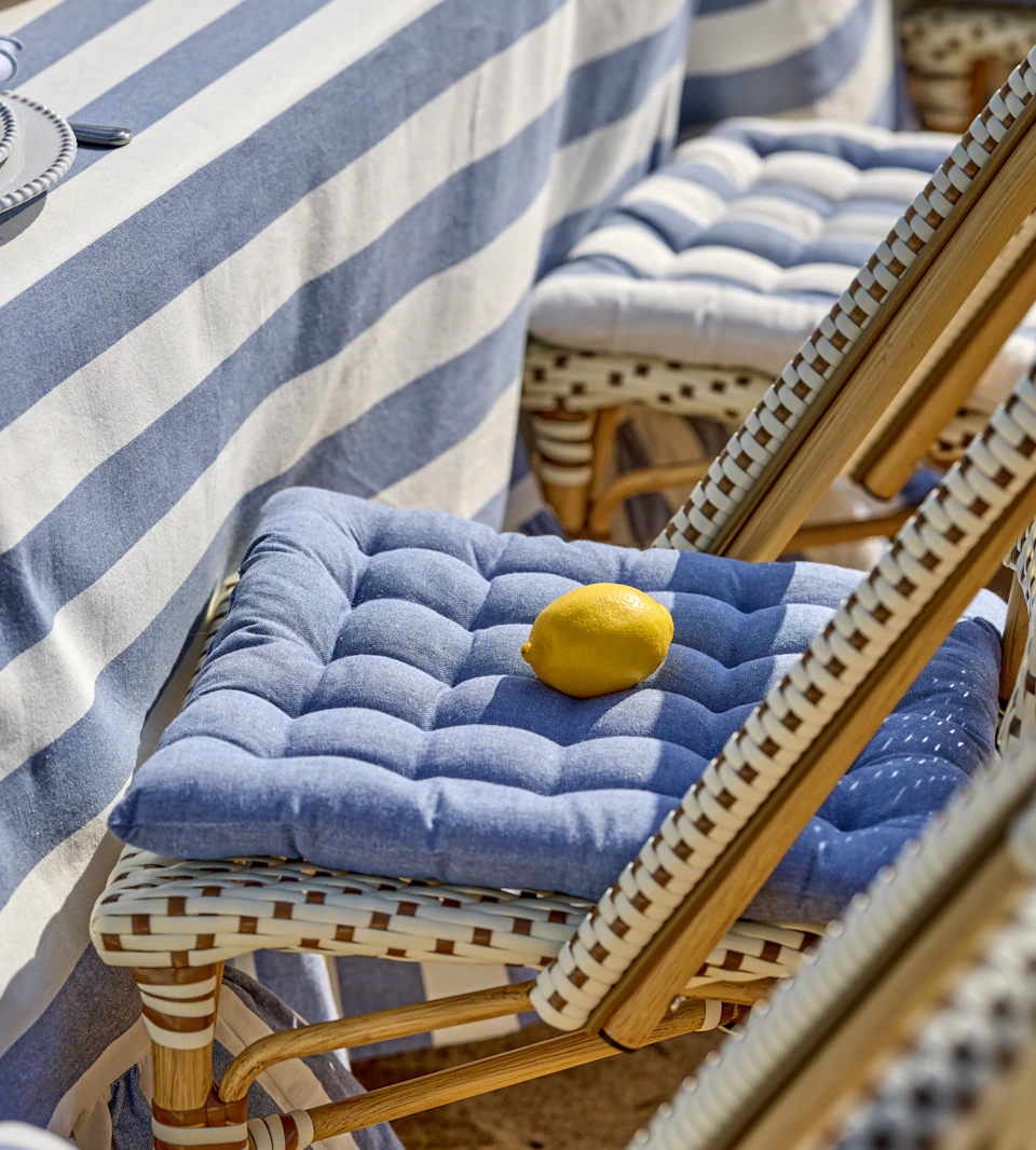 På en stol på stranden ligger en blå sittdyna samt en citron.