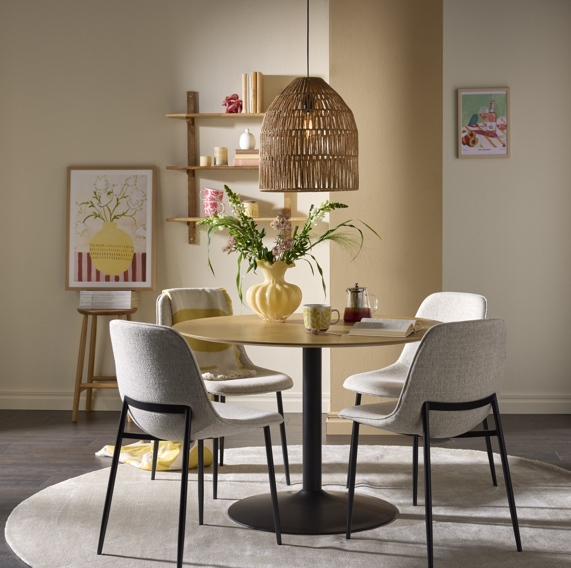 Runt bort i ek med svart pelarfot och fyra grå stolar står i ett ljust matrum.