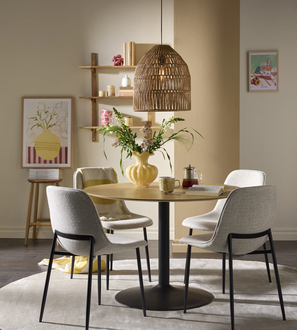 Runt bort i ek med svart pelarfot och fyra grå stolar står i ett ljust matrum.