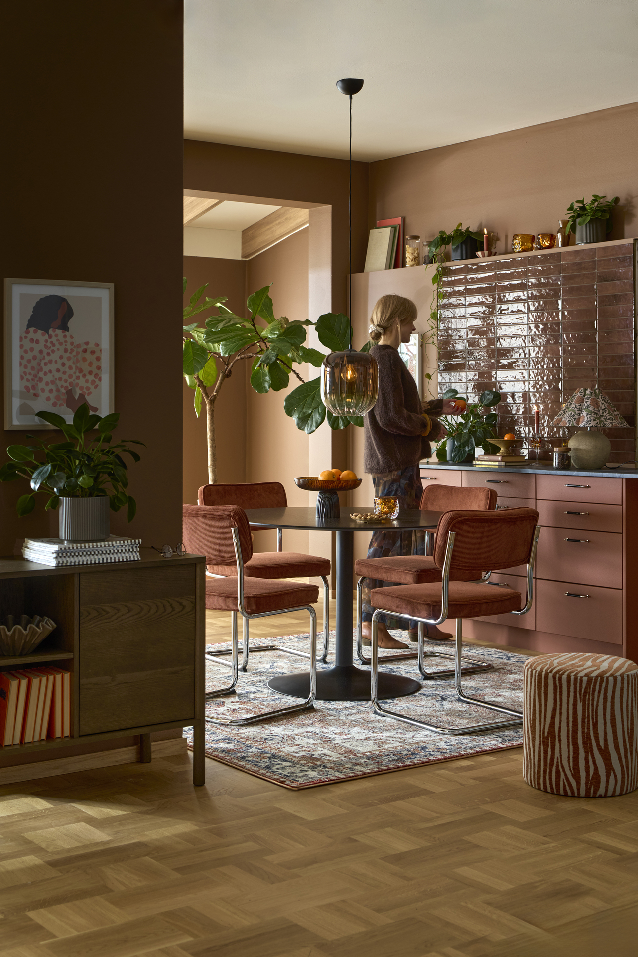 Ett runt svart bord med pelarfot och fyra stolar i rostfärgat manchestertyg.