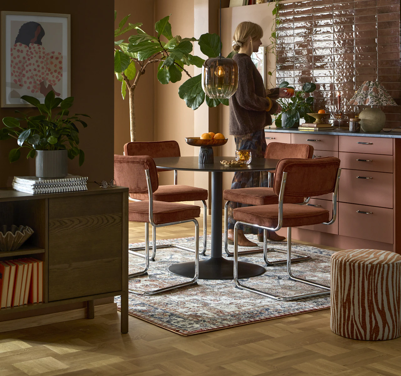 Ett runt svart bord med pelarfot och fyra stolar i rostfärgat manchestertyg.