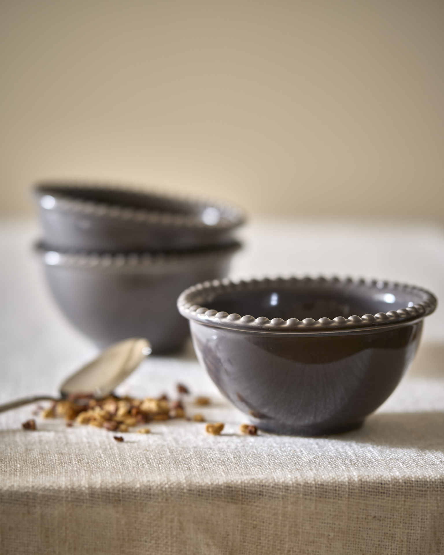 Tre skålar från servisen Leonor står på en beige duk.