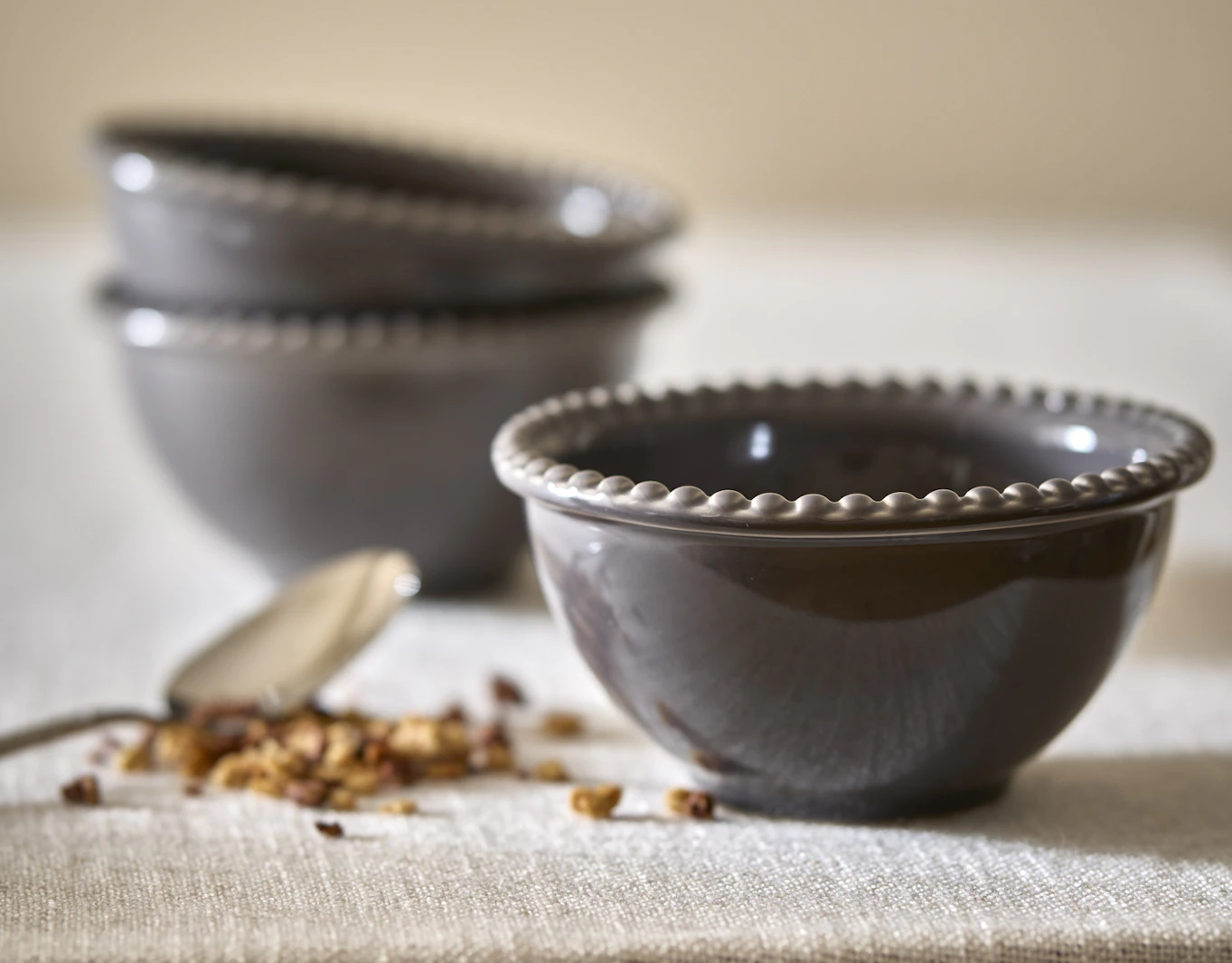 Tre skålar från servisen Leonor står på en beige duk.