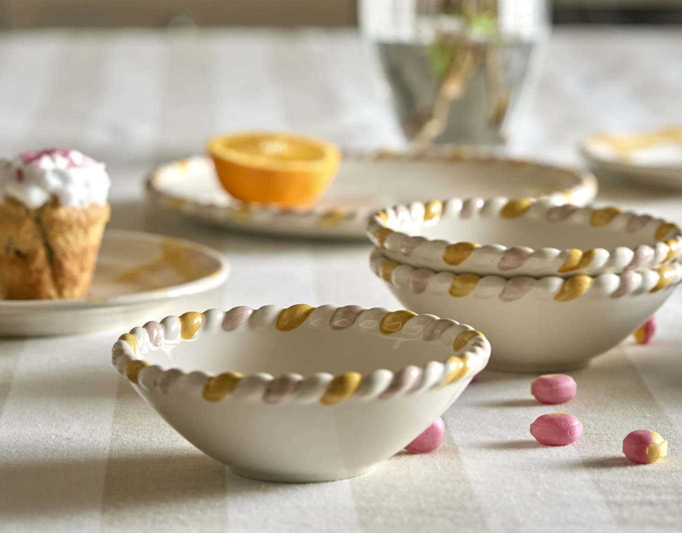 På en randig duk står skålar och tallrikar från servisen Alexia.