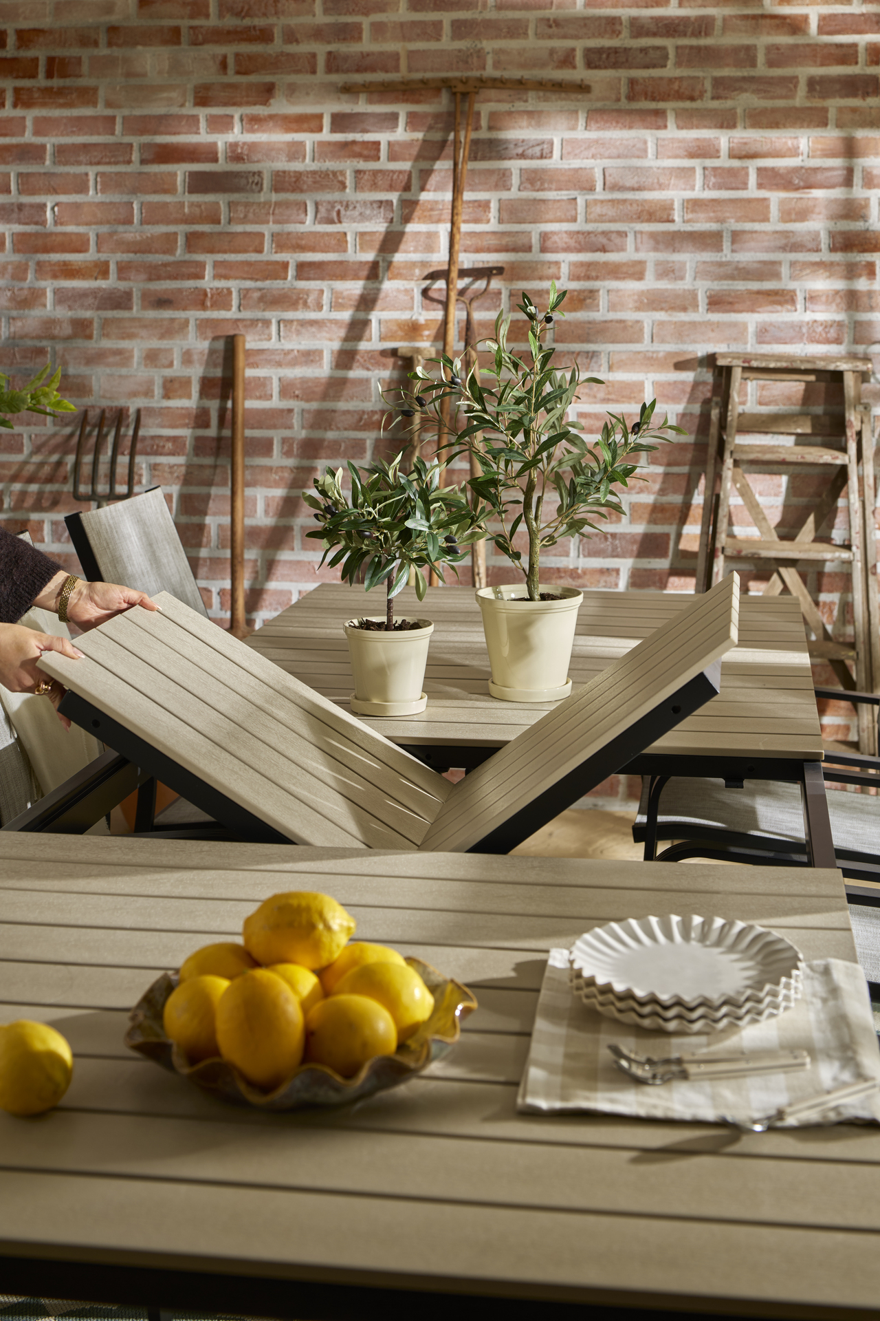 Två händer vecklar ut en smidig butterfly skiva på Modena utebord i svart och beige