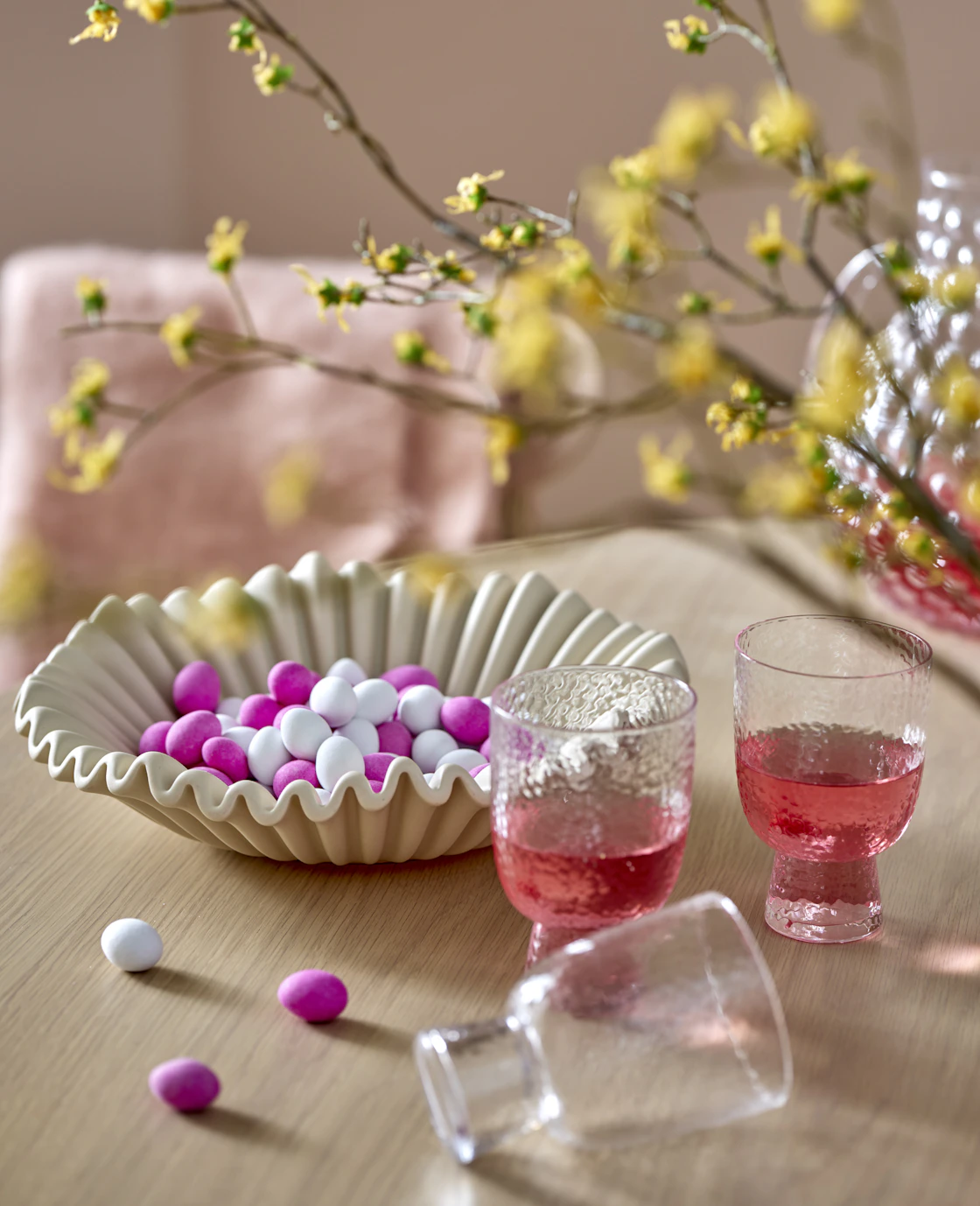 på ett bord står en skål med godis och två glas med rosa dryck i