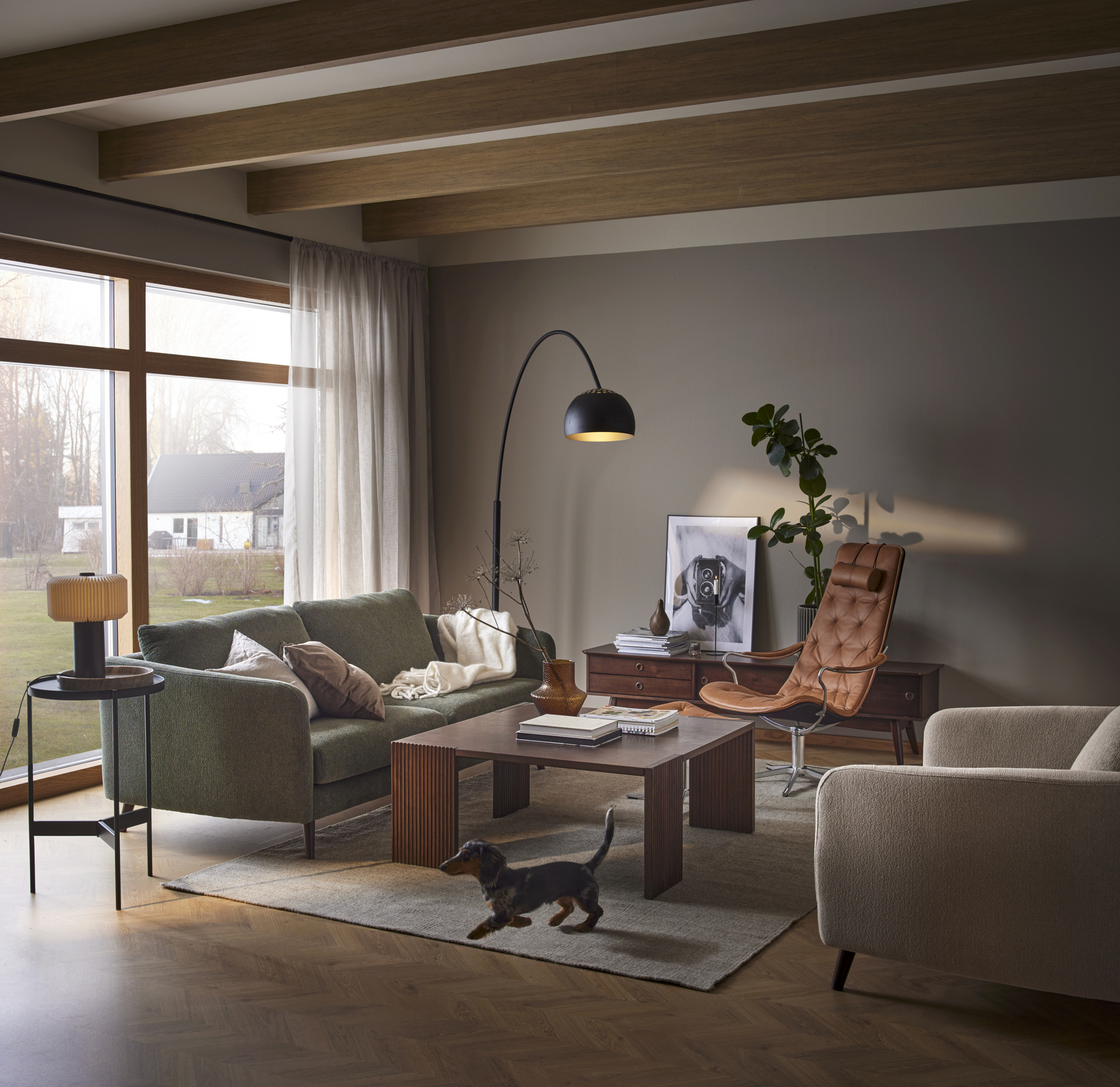 I ett elegant vardagsrum i muriga toner står en brun läderfåtölj