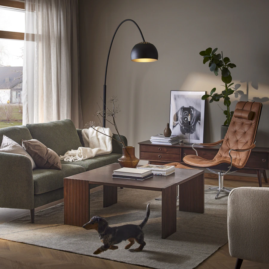 I ett elegant vardagsrum i muriga toner står en brun läderfåtölj