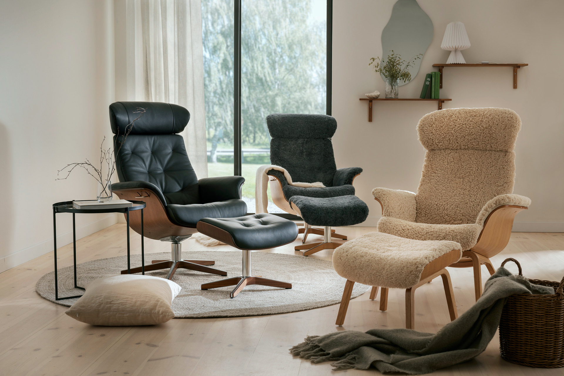 I ett ljust rum med stort fönster står tre fåtöljer i läder och fårskinn