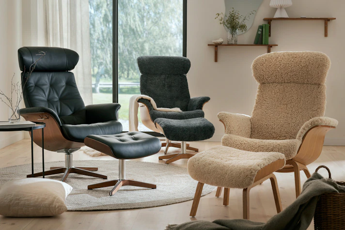 I ett ljust rum med stort fönster står tre fåtöljer i läder och fårskinn