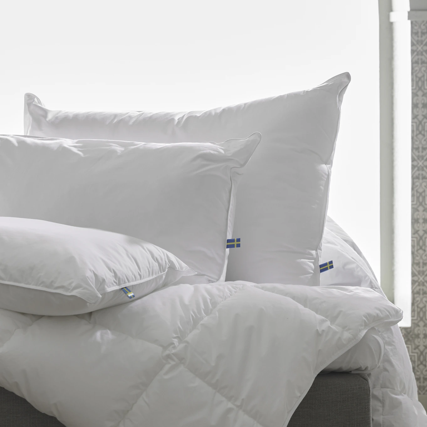 Tre hotellkuddar utan örngott är placerade på en säng.