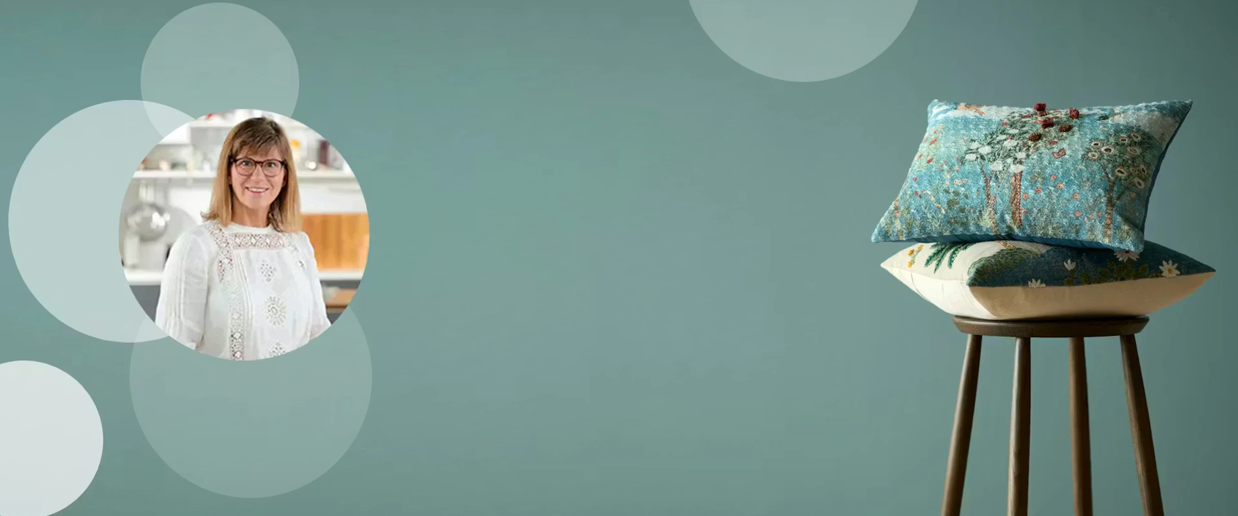 Dekorativ bakgrundsbild med ljusa cirklar på grön vägg där en stol med ett par prydnadskuddar står i högra hörnet.