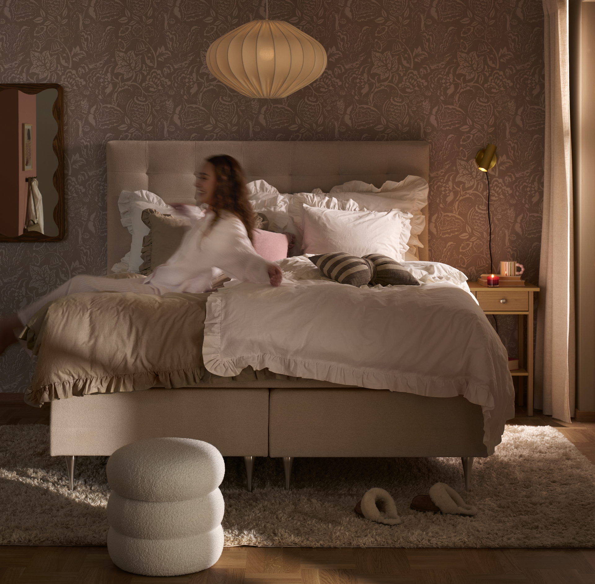 en tjej slänger sig bakåt i en beige kontinentalsäng